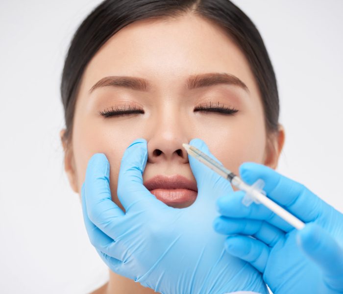 Young woman getting nonsurgical rhinoplasty at plastic surgery clinic